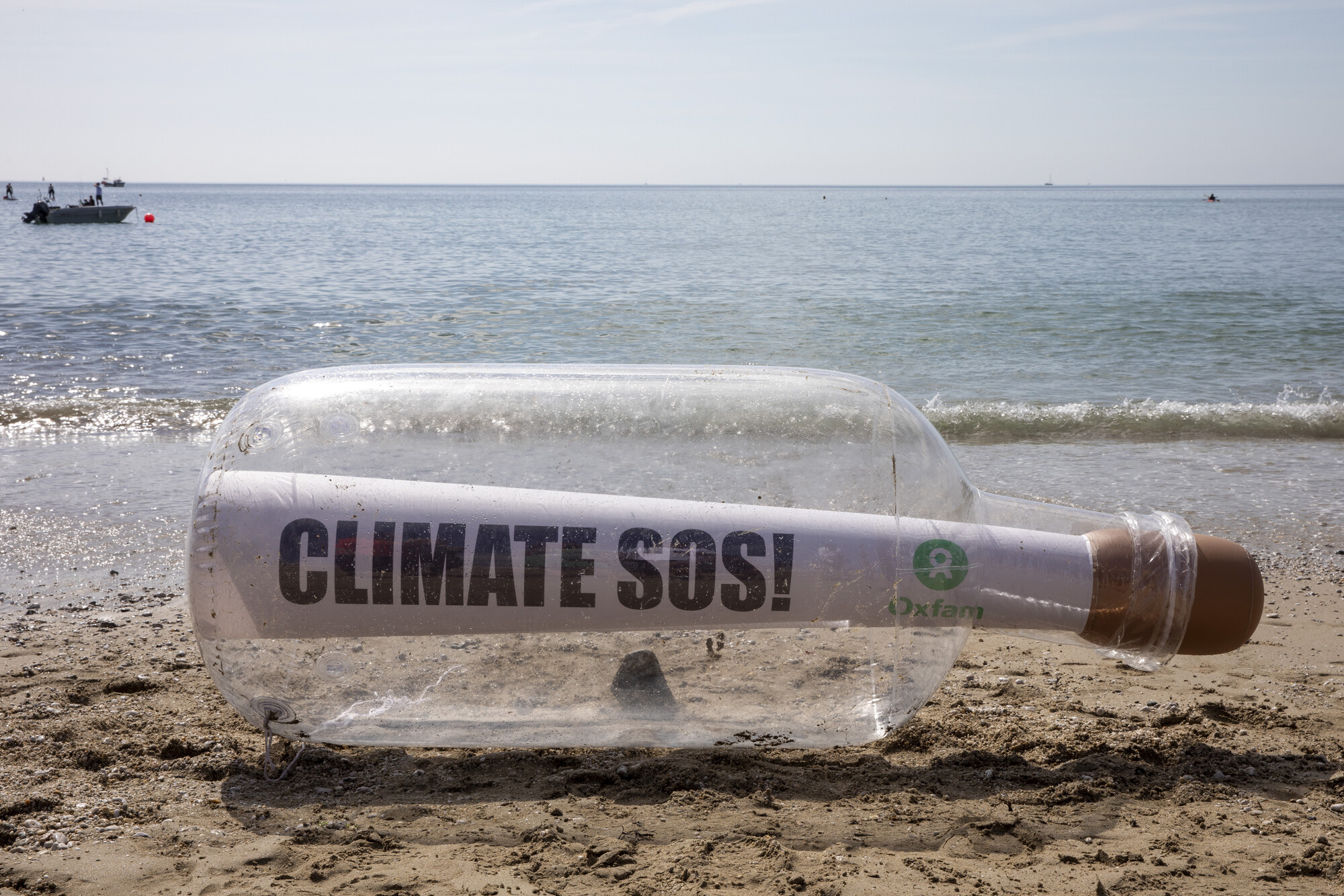 Message reading Climate SOS in a giant bottle on the beach